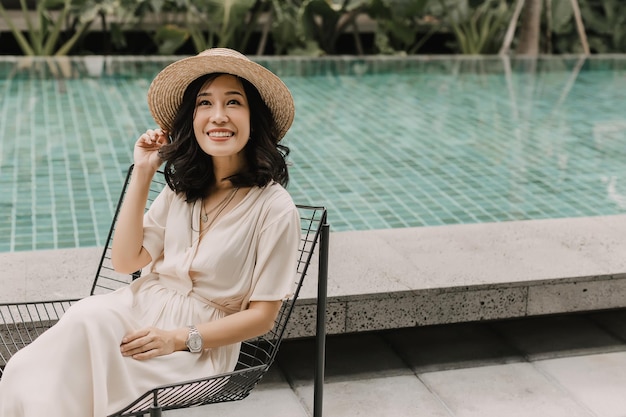 Linda mulher está sentada perto da piscina