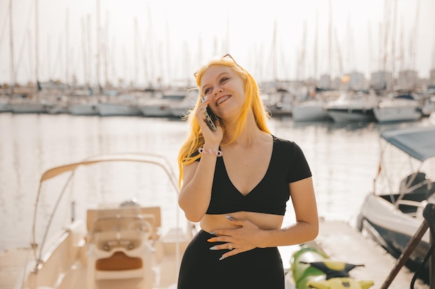 Linda mulher falando ao telefone contra o pano de fundo do mar azul e iates