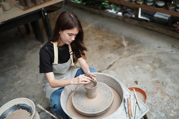 Linda mulher fazendo cerâmica cerâmica nas mãos da roda mulher fechada no hobby de negócios freelance