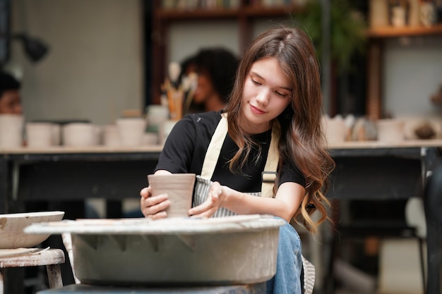 Linda mulher fazendo cerâmica cerâmica nas mãos da roda mulher fechada no hobby de negócios freelance