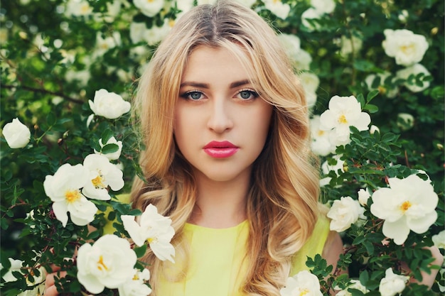 linda mulher feliz com cabelos longos e cacheados cheira flores de rosas brancas ao ar livre closeup retrato de s