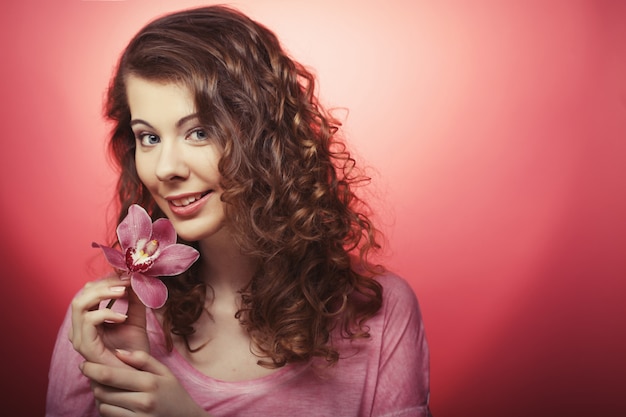 Linda mulher feliz com flor da orquídea sobre rosa