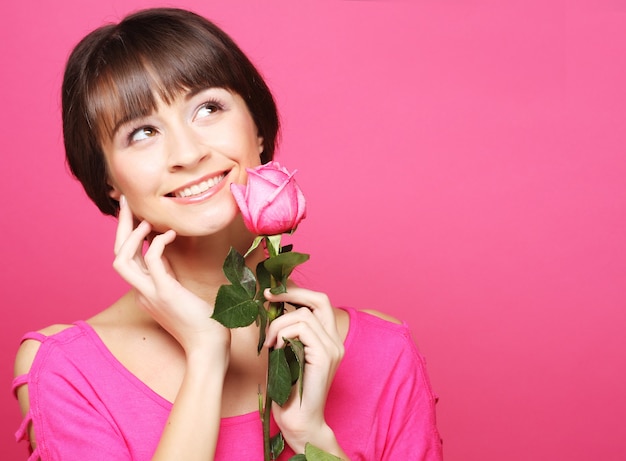 Linda mulher feliz com flor rosa sobre rosa