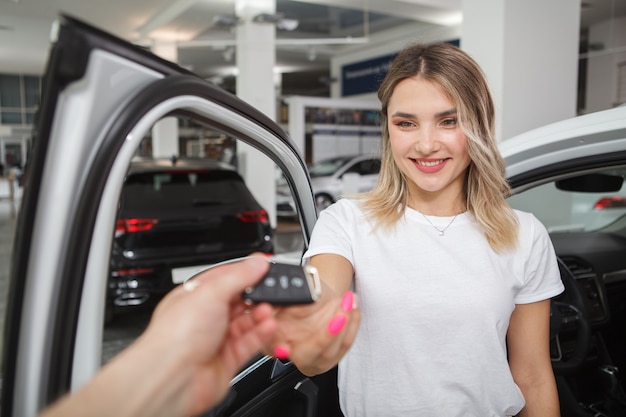Foto linda mulher feliz recebendo as chaves de seu novo automóvel na concessionária