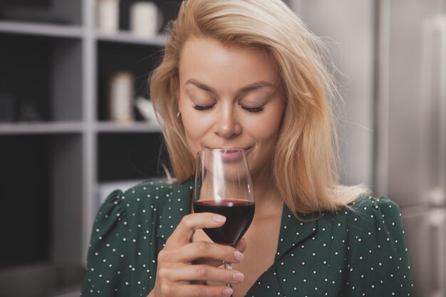 Linda mulher feliz relaxando em casa tomando um copo de vinho