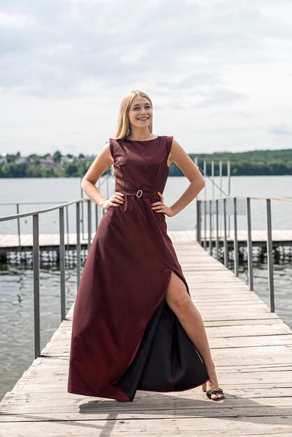 Linda mulher fica usando vestido vermelho escuro longo na natureza