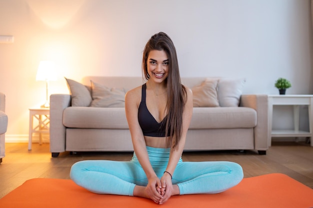 Linda mulher fitness fazendo treino de aquecimento em casa Mulher fitness fazendo exercícios de alongamento esticando as pernasquadriceps Garota em forma vivendo um estilo de vida ativo