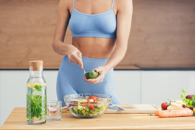 Linda mulher fitness, prepara comida saudável em casa,