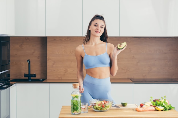 Linda mulher fitness, prepara comida saudável em casa,