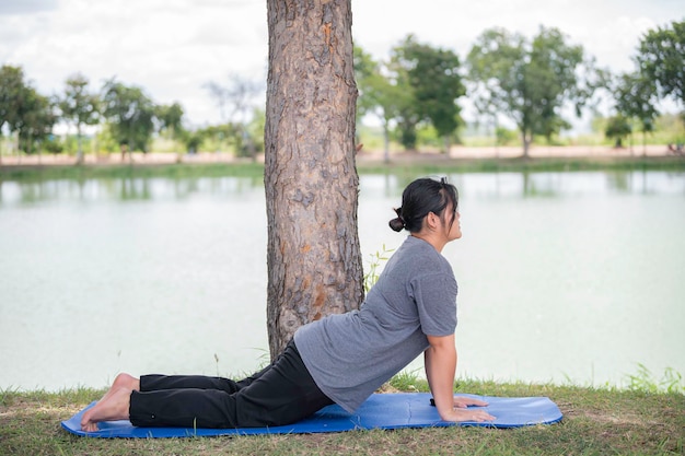 Linda mulher gorda asiática joga ioga no parquePrecisa de corpo magro