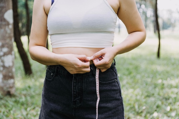 Linda mulher gorda com fita métrica Ela usa a mão para espremer o excesso de gordura que está isolado em um fundo branco Ela quer perder peso o conceito de cirurgia e quebrar a gordura sob o