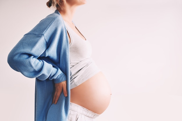 Linda mulher grávida abraçando a barriga em fundo branco. Mulher grávida esperando o nascimento do bebê durante a gravidez. Conceito de saúde materna, visita médica e exame ginecológico.