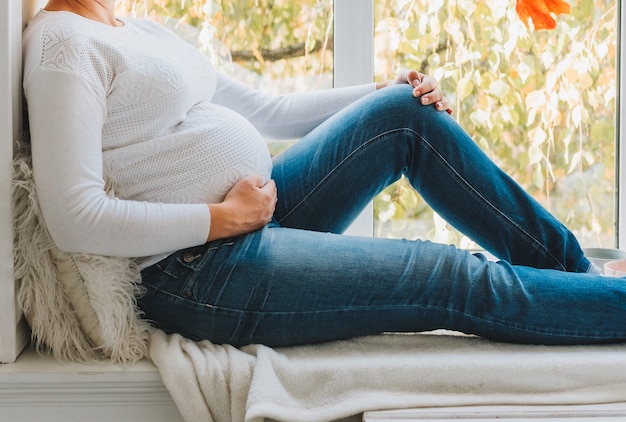 Linda mulher grávida caucasiana vestindo jeans e um top branco