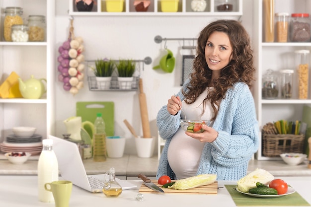 Foto linda mulher grávida com comida na cozinha