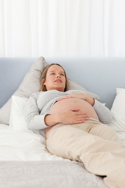 Linda mulher grávida descansando em uma cama