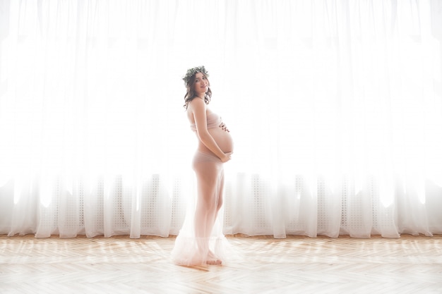 Linda mulher grávida em cena neutra. Imagens de closeup expectante.