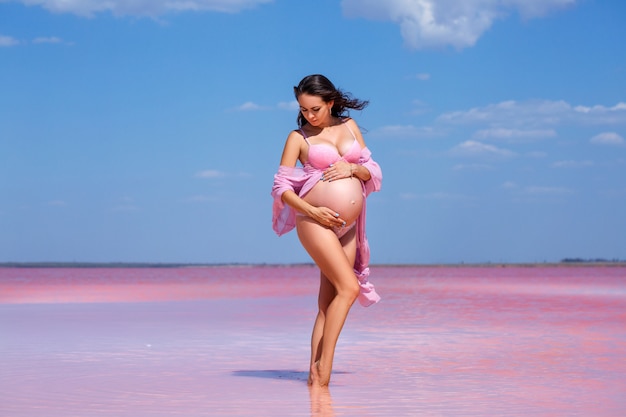 linda mulher grávida em lingerie rosa no lago rosa