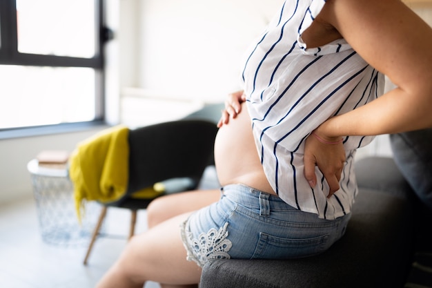 Linda mulher grávida esperando um bebê se sentindo cansada e com dores nas costas