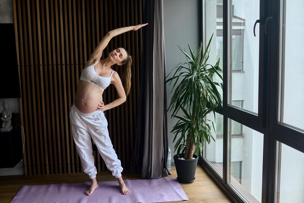 Linda mulher grávida fazendo exercícios em casa