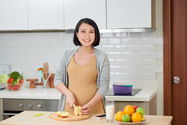 Linda mulher grávida na cozinha com comida saudável