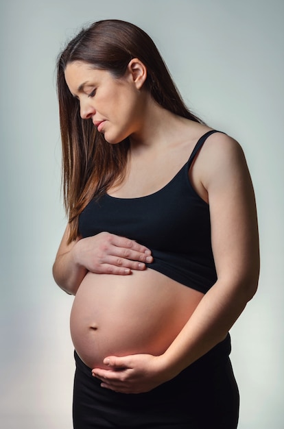 Linda mulher grávida olhando a barriga isolada sobre um fundo branco