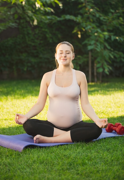 Linda mulher grávida relaxando e meditando ao ar livre