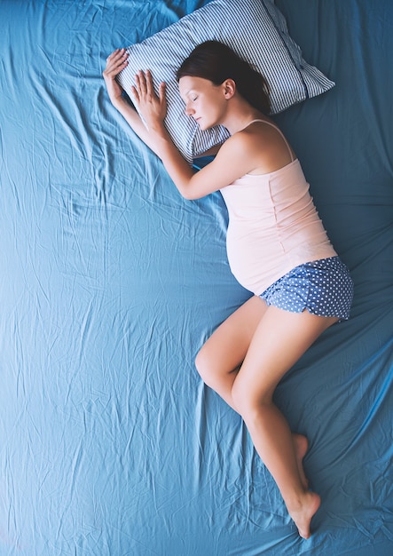 Linda mulher grávida relaxando ou dormindo na cama jovem mãe esperando por um bebê