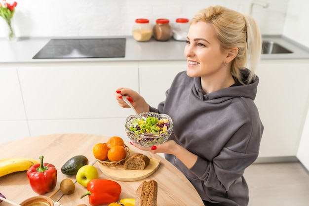 Linda mulher grávida sorrindo com comida saudável de legumes na cozinha. Conceito de comida saudável.