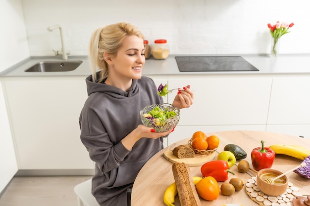 Linda mulher grávida sorrindo com comida saudável de legumes na cozinha. Conceito de comida saudável.