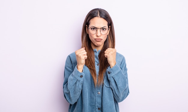 Linda mulher hispânica parecendo confiante, irritada, forte e agressiva, com punhos prontos para lutar em posição de boxe