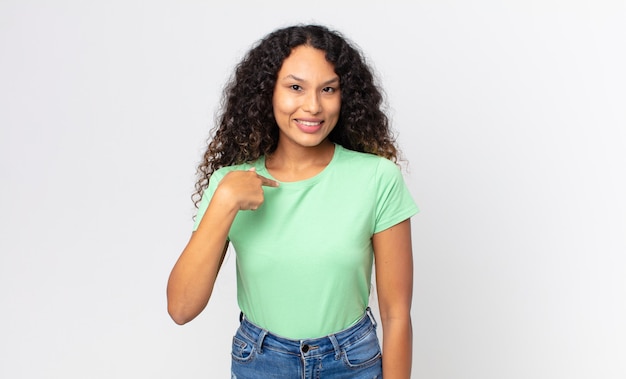 Linda mulher hispânica parecendo feliz, orgulhosa e surpresa, apontando alegremente para si mesma, sentindo-se confiante e altiva