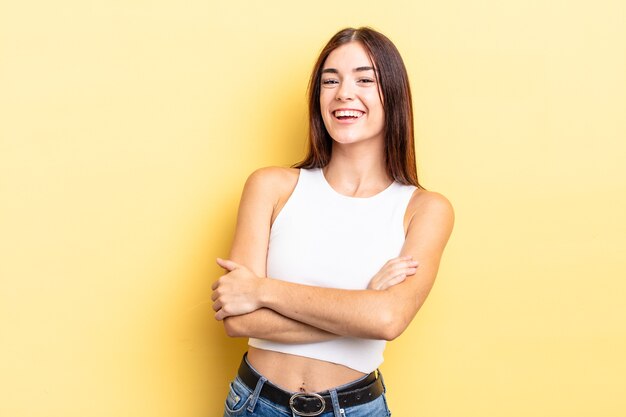 Linda mulher hispânica rindo alegremente com os braços cruzados, numa pose relaxada, positiva e satisfeita