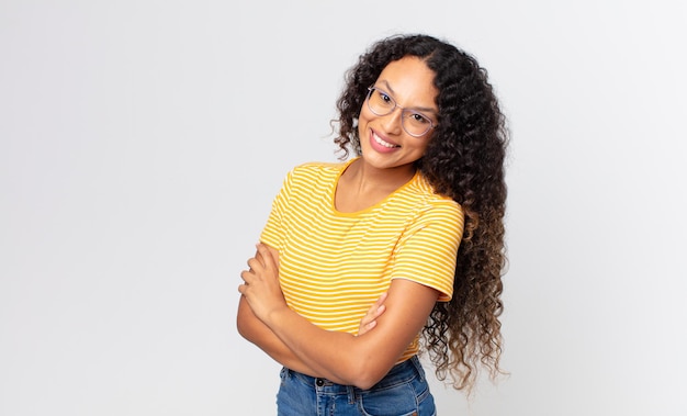 Linda mulher hispânica rindo alegremente com os braços cruzados, numa pose relaxada, positiva e satisfeita