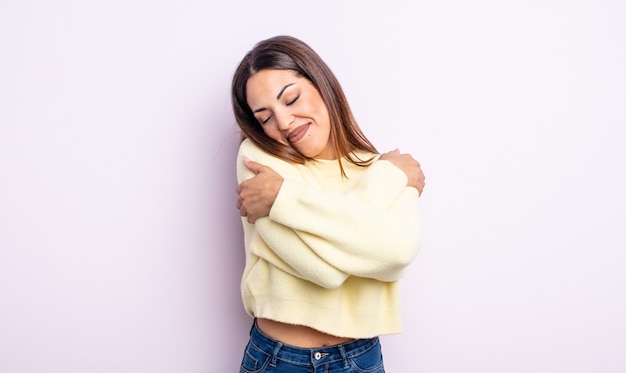 Linda mulher hispânica se sentindo apaixonada, sorrindo, se abraçando e se abraçando, permanecendo solteira, sendo egoísta e egocêntrica