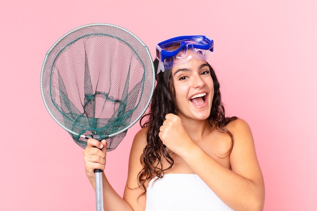 Linda mulher hispânica se sentindo feliz e enfrentando um desafio ou comemorando com óculos e rede de pesca