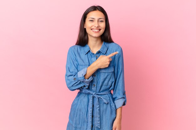 Linda mulher hispânica sorrindo alegremente, feliz e apontando para o lado