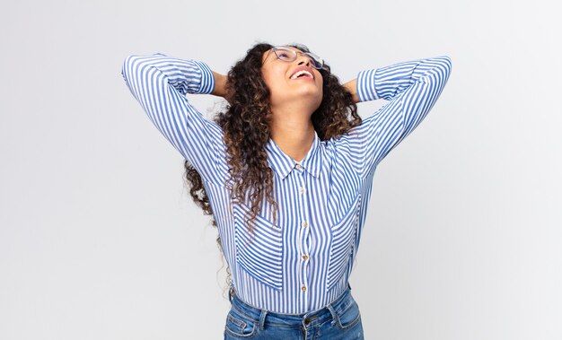 Foto linda mulher hispânica sorrindo e se sentindo relaxada, satisfeita e despreocupada, rindo positivamente e relaxando