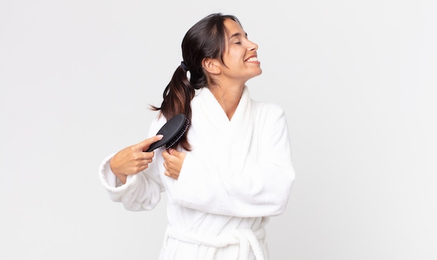 Linda mulher hispânica usando roupão de banho e segurando uma escova de cabelo