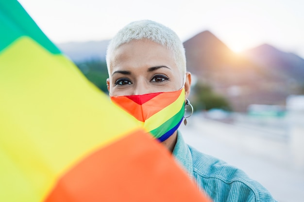 Linda mulher homossexual latina com bandeira do orgulho LGBT arco-íris ao ar livre