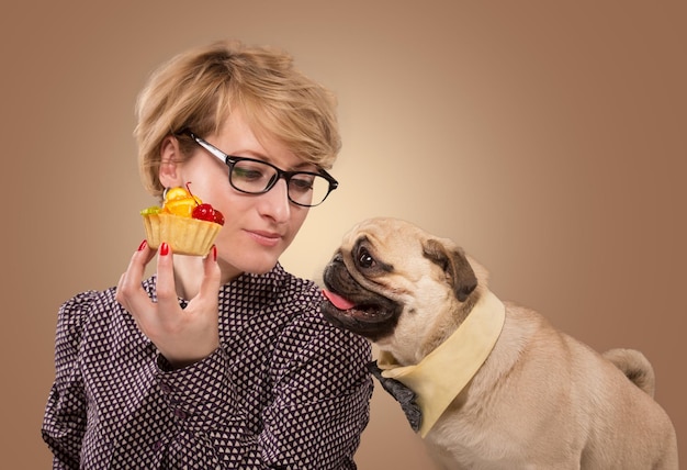 Linda mulher impedindo seu cachorro de comer bolo