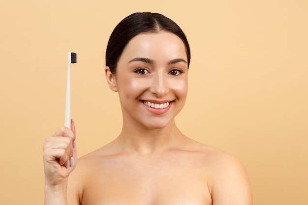 Linda mulher indiana segurando a escova de dentes e sorrindo para a câmera fazendo atendimento odontológico