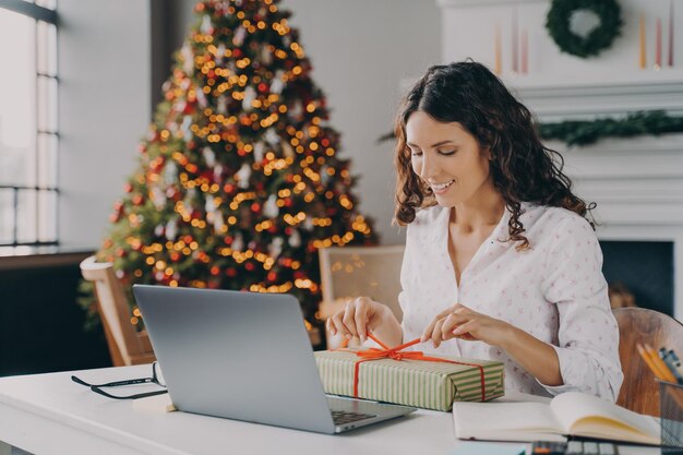 Linda mulher italiana de negócios decorando o presente de natal no local de trabalho durante as festas de natal