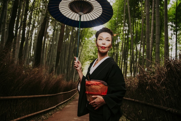 Linda mulher japonesa sênior andando na floresta de bambu