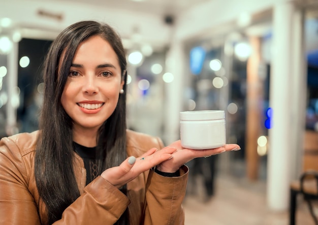 Linda mulher latina segura recipiente branco creme na mão com espaço de cópia para retrato de anúncio