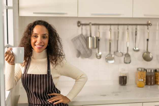 Foto linda mulher latina tomando café na cozinha