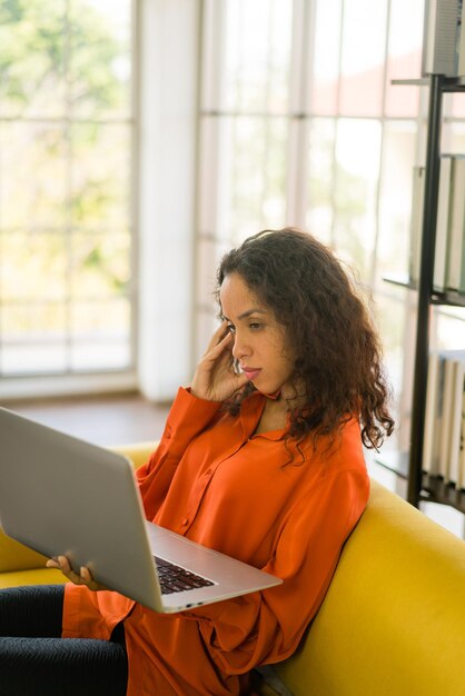 Foto linda mulher latina trabalhando com laptop no sofá com sensação de cansaço