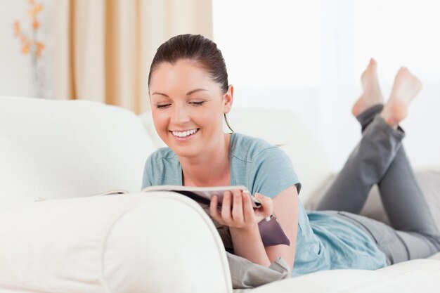 Linda mulher lendo uma revista enquanto estava deitada em um sofá