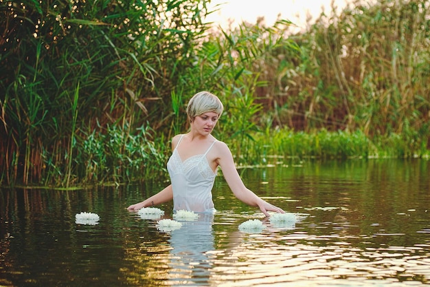 Linda mulher loira com cabelo curto nadando, relaxando no lago ao pôr do sol. Férias de verão.