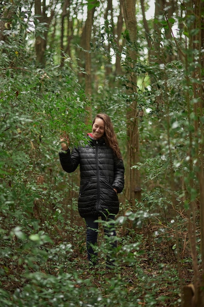Linda mulher loira de meia-idade sozinha caminhando pela floresta entre as folhas das árvores na floresta. 40 anos.