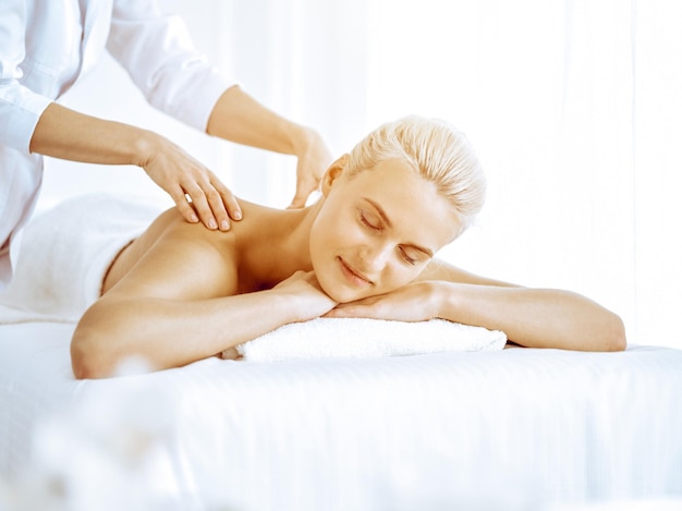Linda mulher loira desfrutando de massagem nas costas no centro de spa Beleza e estilo de vida